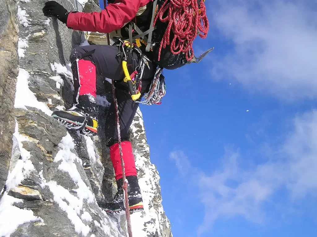 An alpinist climbing sheer wall of a mountain.
