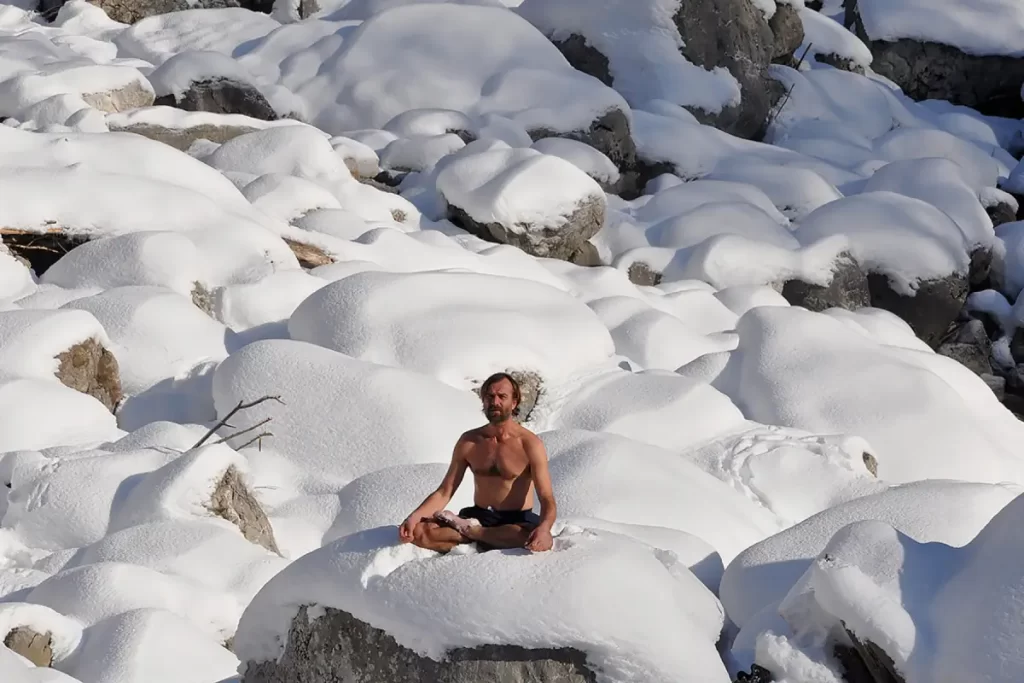 Wim Hof on a snow-covered boulder.